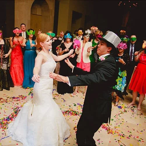 Lively wedding reception at The Bell Tower on 34th with masked guests, confetti, and dancing newlyweds in style.